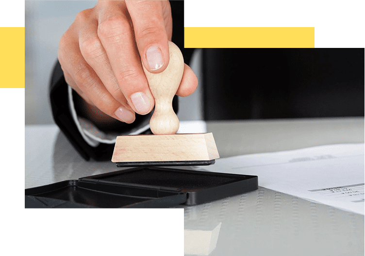 A person is holding a rubber stamp on top of a table.